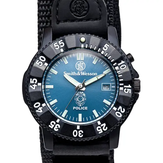 Zegarek policyjny Smith & Wesson Smith & Wesson Police Watch. Korpus ze stali nierdzewnej, obrotowa luneta, niebieska tarcza z logo policji, datownik, elektroniczne podświetlenie, wodoszczelność 3ATM, nylonowy pasek. Wymiary: 40 x 13 mm.